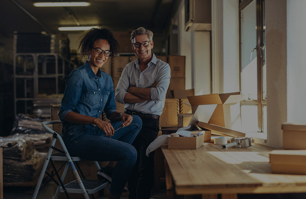 A man and a woman smiling while in a warehouse space